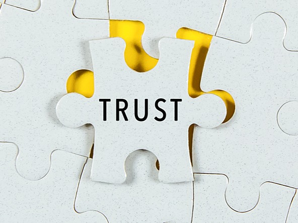 white jigsaw puzzle with one piece loose, with the word trust on it